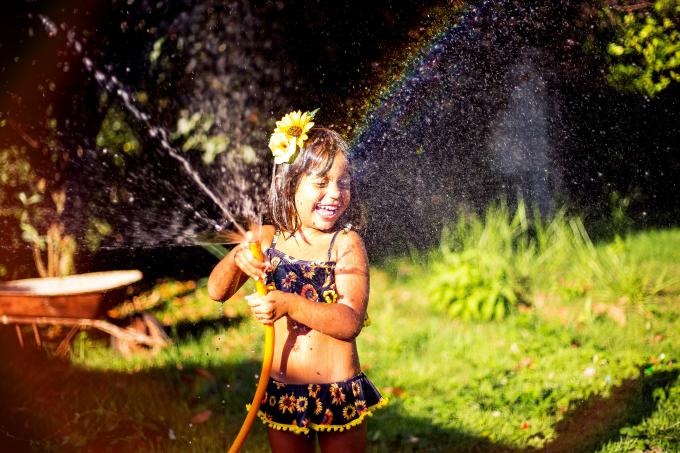 Smiling Girl Playing With Water Hose