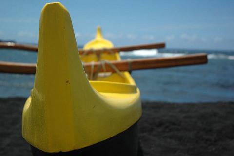 Yellow outrigger canoe on black sand beach in Hawaii